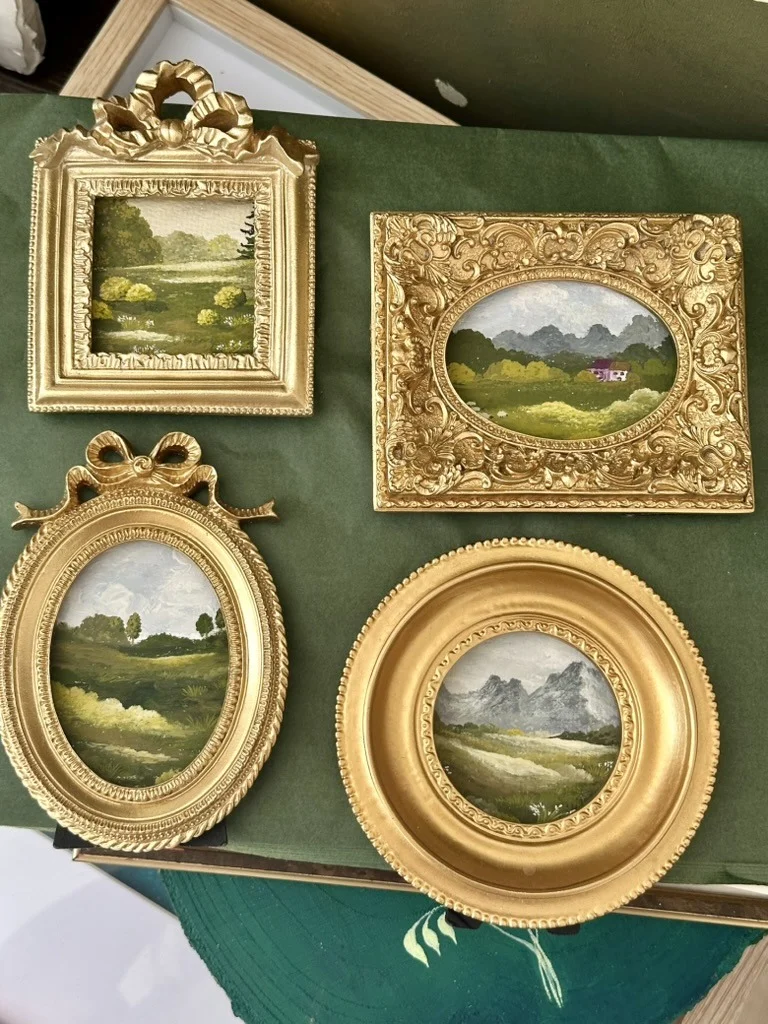 Miniature landscapes in gilded antique frames laid out on green cloth